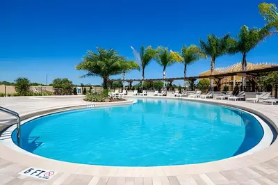 a swimming pool at a resort with chairs and palm trees at Townhouse 3Q Perto da Disney c/ Mickey Room in Kissimmee