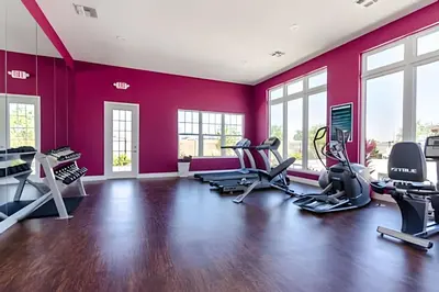 a gym with red walls and treadmills and ellipticals at Townhouse 3Q Perto da Disney c/ Mickey Room in Kissimmee