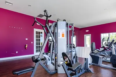 a gym with red walls and tread machines at Townhouse 3Q Perto da Disney c/ Mickey Room in Kissimmee