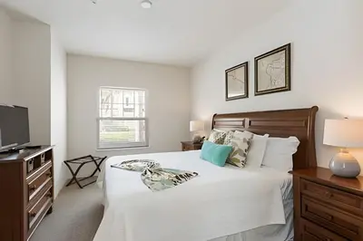a white bedroom with a bed and a television at Townhouse 3Q Perto da Disney c/ Mickey Room in Kissimmee