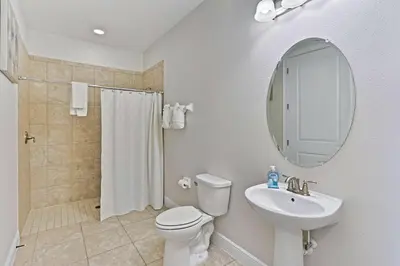 a bathroom with a toilet and a sink and a mirror at Magical Memories Villa 10bd Near Disney in Orlando