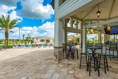 a patio with tables and chairs and a bar at Apto 2Q Storey Lake — Vista Lago e Clube in Kissimmee