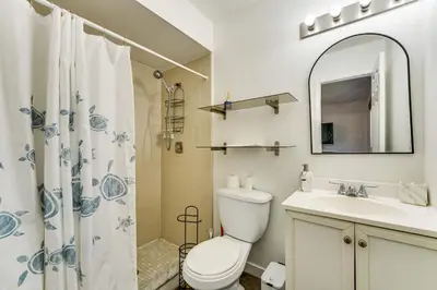 a bathroom with a toilet and a sink and a mirror at 3 Mi to SeaWorld! Suburban Home with Screened Porch in Orlando