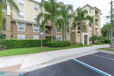 a building with palm trees in front of a parking lot at Apartamento 3Q no Vista Cay Resort in Orlando