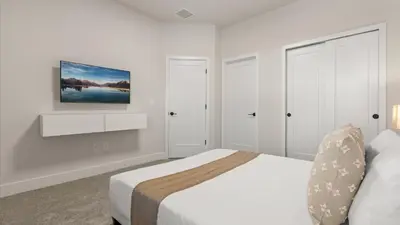 a white bedroom with a bed and a painting on the wall at Stunning Townhome with Private Pool & Games Room in Orlando