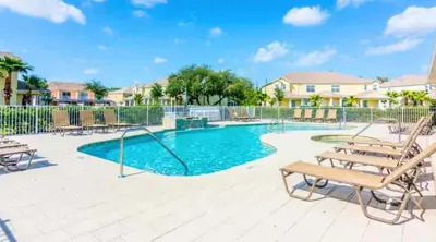 a swimming pool with chairs and a bench at Stunning Townhome with Private Pool & Games Room in Orlando