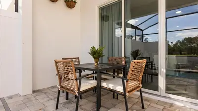 a black table and chairs on a patio with windows at Stunning Townhome with Private Pool & Games Room in Orlando