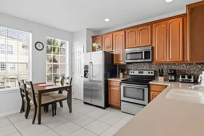 a kitchen with stainless steel appliances and a table at Casa 3Q Vista Cay – Perto da Universal & Centro in Orlando