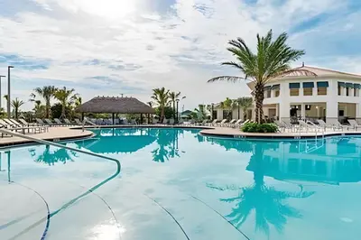 a swimming pool with chairs and a building at Villa Sanches 4Q c/ Piscina – Storey Lake Resort in Kissimmee