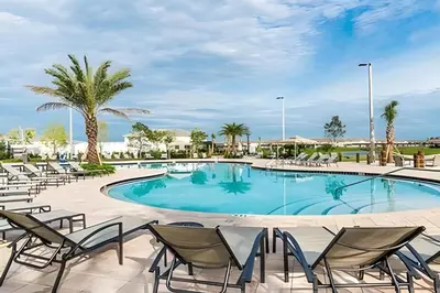a large swimming pool with chairs and palm trees at Villa Sanches 4Q c/ Piscina – Storey Lake Resort in Kissimmee