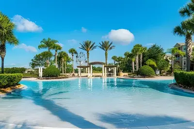 a large pool with palm trees in a resort at Condo 3Q Windsor Hills — Perto da Disney in Orlando