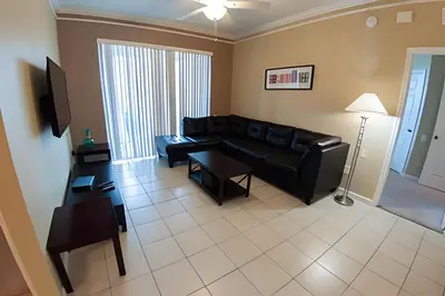 a living room with a black leather couch and a table at Condo 3Q Windsor Hills — Perto da Disney in Orlando
