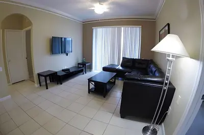 a living room with a black leather couch and a table at Condo 3Q Windsor Hills — Perto da Disney in Orlando