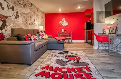 a living room with a couch and a red wall at Mickey's Hideaway Condo Near Disney in Orlando