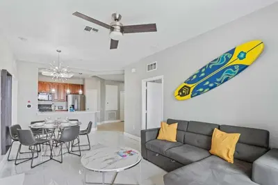 a living room with a couch and a surfboard on the wall at Condo 3Q Vista Cay c/ Varanda e Piscina Resort in Orlando