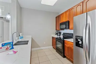 a kitchen with a stainless steel refrigerator and wooden cabinets at Condo 3Q Vista Cay c/ Varanda e Piscina Resort in Orlando