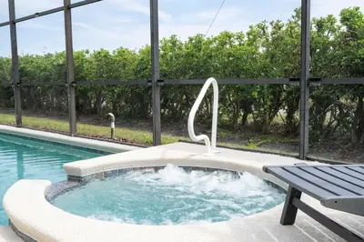 a hot tub with a bench next to a swimming pool at Enchanting 6BR, Themed Rooms, Game Room and Resort in Kissimmee