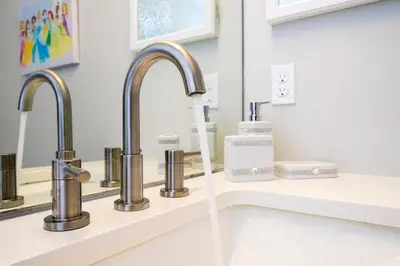 a bathroom sink with two faucets and a mirror at Enchanting 6BR, Themed Rooms, Game Room and Resort in Kissimmee