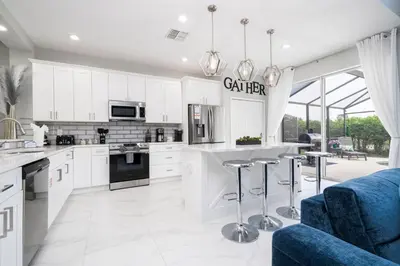 a kitchen with white cabinets and a blue couch at Enchanting 6BR, Themed Rooms, Game Room and Resort in Kissimmee