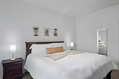 a white bedroom with a large white bed and a nightstand at Casa 3Q Moderna perto da Disney e acesso ao Resort in Kissimmee