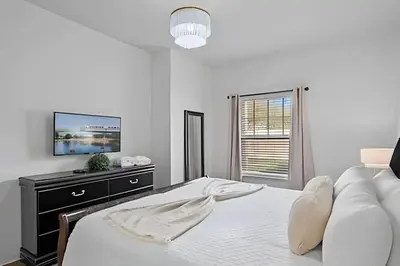 a white bedroom with a bed and a flat screen tv at Casa 3Q Moderna perto da Disney e acesso ao Resort in Kissimmee