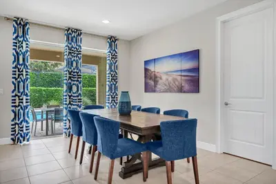 a dining room with a wooden table and blue chairs at Spacious Fun Retreat With Private Pool And Game Room Near Disney And Waterpark & Resort Access At Encore Resorts Reunion - 7659Wi in Orlando