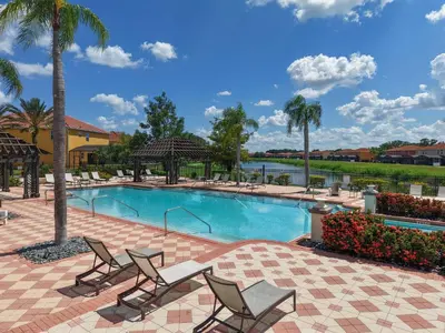 a swimming pool with two chairs and palm trees at Refúgio c/ Vista do Lago e Piscina – Perto Disney in Kissimmee