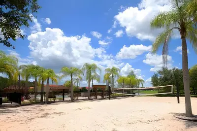 a volleyball court with palm trees and a net at Conforto e Diversão no Bella Vida – 3Q+ Piscina in Kissimmee