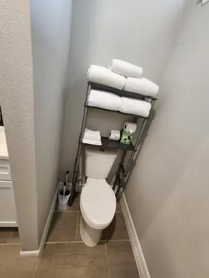 a bathroom with a toilet and towels on a shelf at Orlando Luxury Home in Orlando
