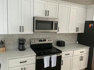 a kitchen with white cabinets and a stove and microwave at Orlando Luxury Home in Orlando