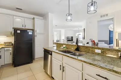 a kitchen with white cabinets and a black refrigerator at Apartamento Vista Cay: ao lado do UNIVERSAL in Orlando