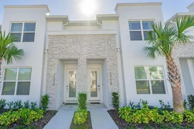 a white house with palm trees in front of it at Disney Escape 3BR Home Pool in Orlando