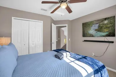 a bedroom with a blue bed with a ceiling fan at Disney Pool Retreat Modern Home Sleeps 8 in Kissimmee