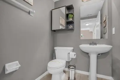 a bathroom with a white toilet and a sink at Disney Pool Retreat Modern Home Sleeps 8 in Kissimmee