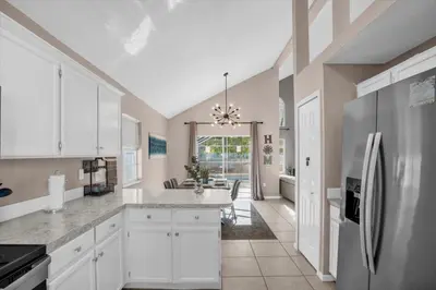 a kitchen with white cabinets and a refrigerator at Disney Pool Retreat Modern Home Sleeps 8 in Kissimmee