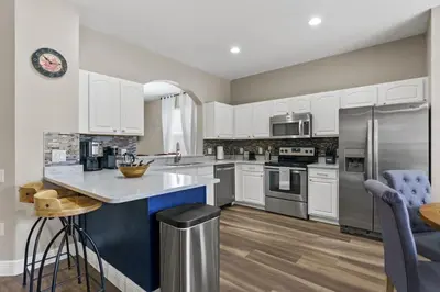 a kitchen with white cabinets and a blue island at Cozy Pool Villa Minutes Drive to Disney in Orlando