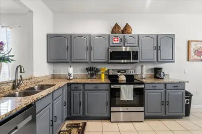 a kitchen with gray cabinets and stainless steel appliances at Large Family Retreat Pool BBQ Disney Parks Nearby in Orlando