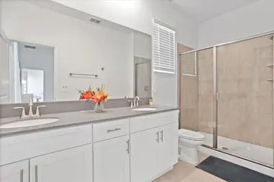 a bathroom with two sinks and a toilet and a shower at Bright Pool Villa Gated Resort Disney Shuttle Nearby in Kissimmee
