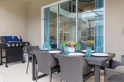a dining room table with chairs and a grill at Bright Pool Villa Gated Resort Disney Shuttle Nearby in Kissimmee