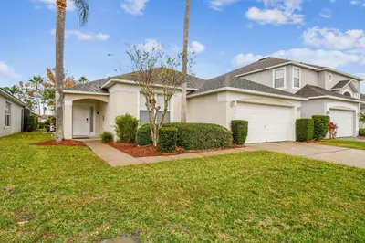 a house with a driveway and palm trees at Casa c/ Piscina Privativa e Game Room in Kissimmee