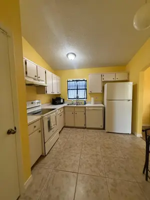 a kitchen with white appliances and yellow walls at Sunny Orlando Oasis - Cozy 2 Bedroom house near Disney in Kissimmee