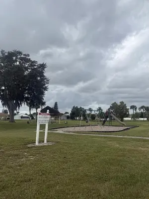 a park with a playground with a sign in the grass at Sunny Orlando Oasis - Cozy 2 Bedroom house near Disney in Kissimmee
