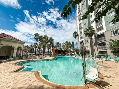 a swimming pool in a hotel with chairs and palm trees at Flats moderno 4min da Universal - The Point Orlando in Orlando