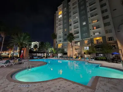 a swimming pool at night with buildings at Flats moderno 4min da Universal - The Point Orlando in Orlando