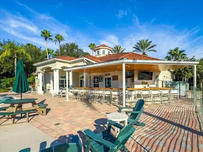a patio with chairs and tables and a house at Elegant Emerald Island – Near Disney in Kissimmee