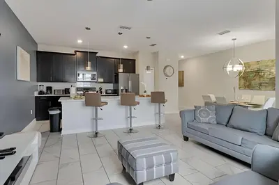 a living room with a couch and a kitchen at Casa Familiar 10min da Disney + Piscina Privativa in Kissimmee