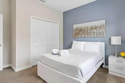 a bedroom with a white bed with a white headboard at Casa 5Q Familiar — 10min da Disney + Piscina in Kissimmee