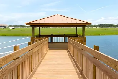 a wooden boardwalk leading to a gazebo over a lake at Casa 5Q Familiar — 10min da Disney + Piscina in Kissimmee