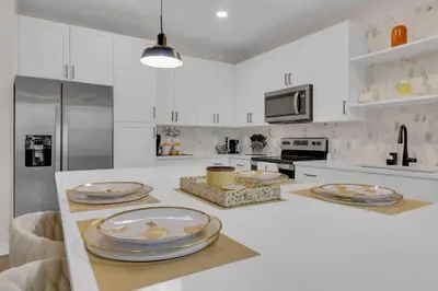 a white kitchen with plates on a counter at Modern 2 Bedrm Apartment with fast Wi-fi - Apartment in Orlando