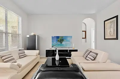 a living room with two white couches and a piano at Casa 5Q Piscina Resort Windsor Hills Disney in Orlando